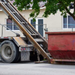 Empty,Construction,Dumpster,Being,Unloaded,From,Truck,At,Residential,Construction