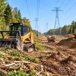 Heavy equipment clearing brush and moving earth beneath high-voltage power lines in a utility corridor in Monclova Township, Ohio.